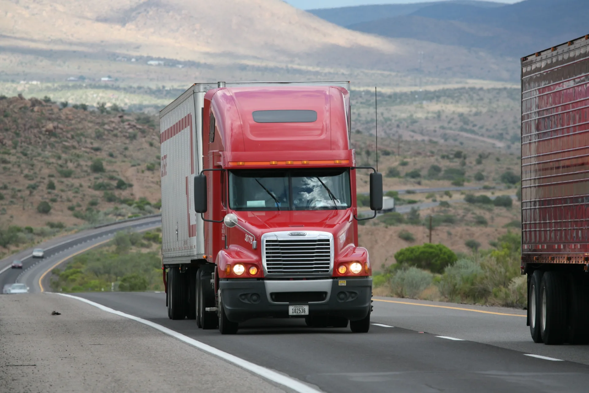 SMARTWAY 95 red semi truck hauling a dry van trailer on a desert highway